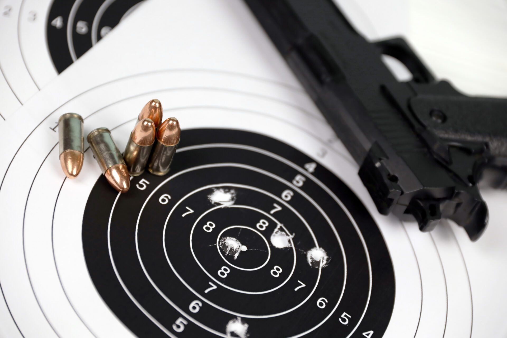 Gun and many bullets shooting targets on white table in shooting range polygon. Training for aiming and shooting accuracy